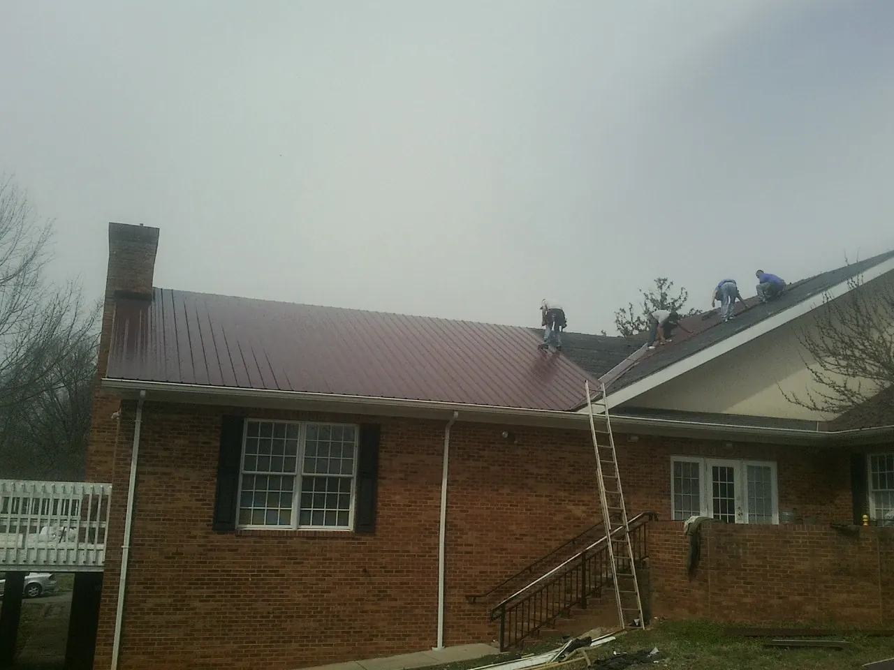 Crew setting red metal roofing panels on a brick home in Augusta