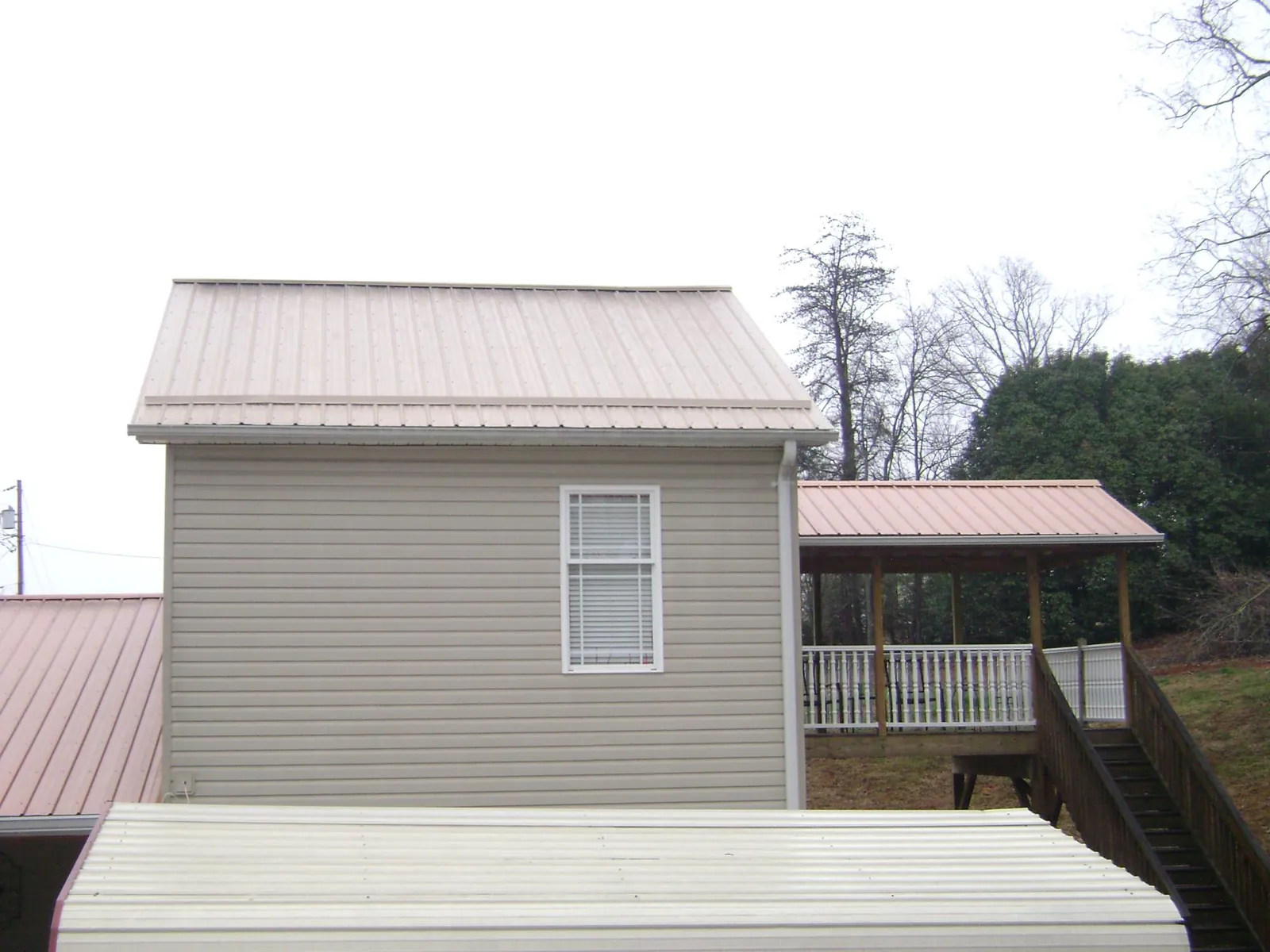 Tan metal roofs on a two story addition and attached porch, from a Roof Replacement job in Augusta